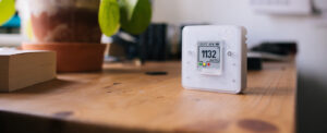 iaq monitor sits on a well-lit desk with a houseplant